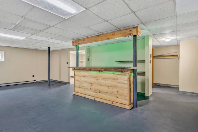 bar featuring baseboard heating, baseboards, concrete flooring, and a paneled ceiling