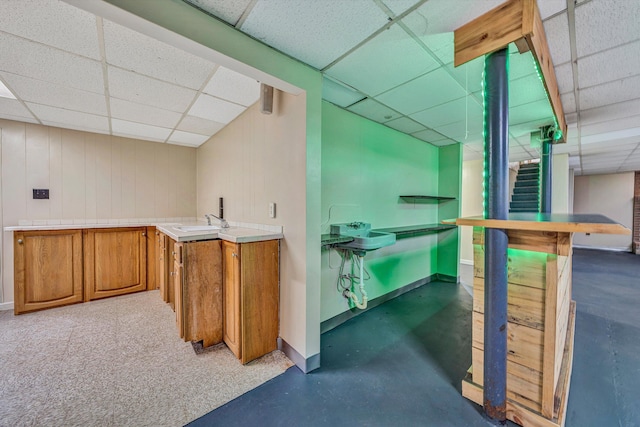 interior space with stairway, baseboards, a drop ceiling, and a sink