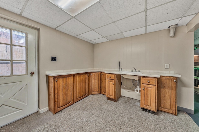 interior space with a paneled ceiling and a sink