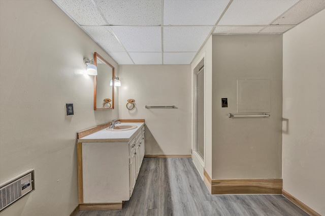 full bath featuring vanity, wood finished floors, visible vents, a stall shower, and a drop ceiling