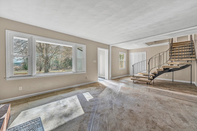 carpeted entrance foyer with stairway and baseboards