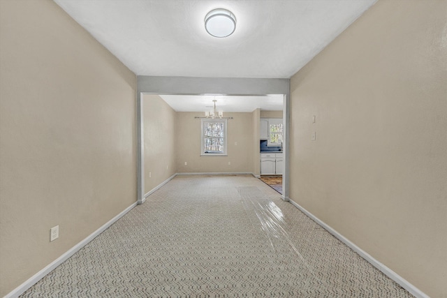 unfurnished room featuring an inviting chandelier and baseboards