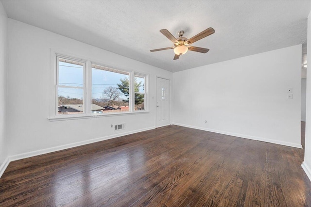 spare room featuring dark wood-type flooring, baseboards, and visible vents