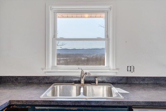 kitchen with dark countertops, dishwasher, and a sink