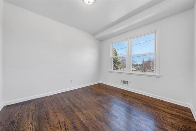 empty room with visible vents, dark wood-type flooring, and baseboards