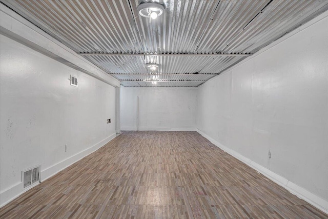 below grade area featuring wood finished floors, visible vents, and baseboards