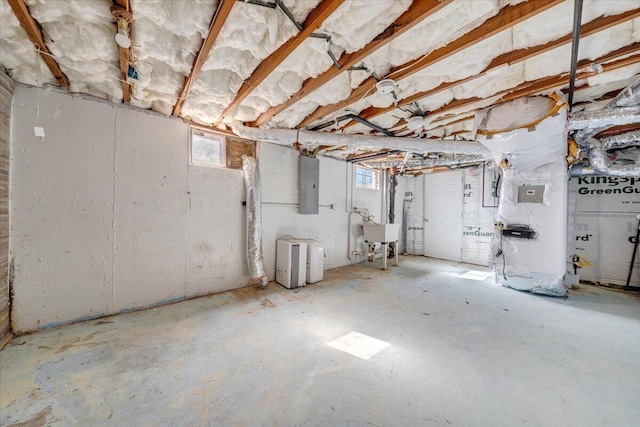 basement featuring electric panel, plenty of natural light, and a sink