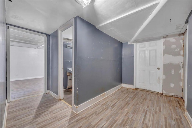 additional living space featuring baseboards, lofted ceiling, and light wood-style flooring