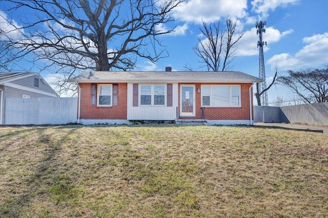 view of front of property featuring a front lawn, fence, and brick siding