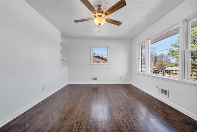 empty room with visible vents, a textured ceiling, and hardwood / wood-style floors