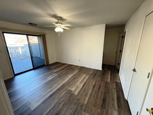 unfurnished bedroom with visible vents, ceiling fan, baseboards, dark wood finished floors, and access to outside