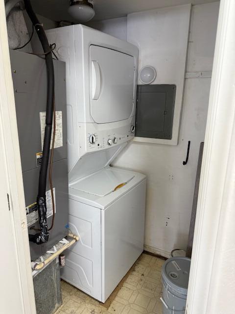 laundry area featuring electric panel, laundry area, light floors, and stacked washer / dryer