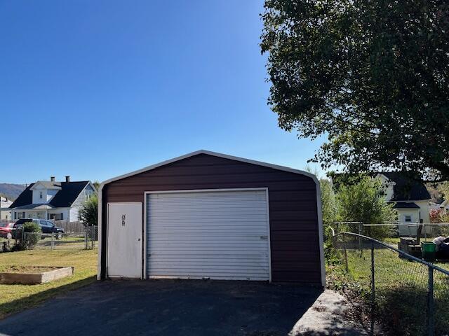 detached garage featuring driveway and fence