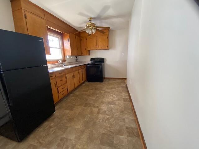 kitchen featuring black appliances, a sink, light countertops, baseboards, and ceiling fan