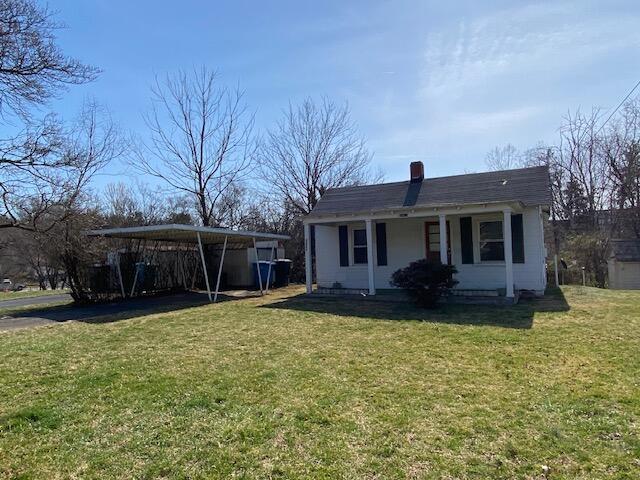 rear view of house with a lawn, a chimney, and a carport