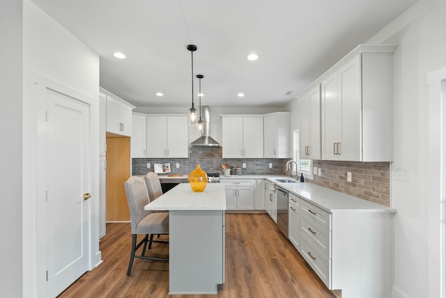 kitchen featuring wood finished floors, a sink, stainless steel dishwasher, wall chimney exhaust hood, and a center island