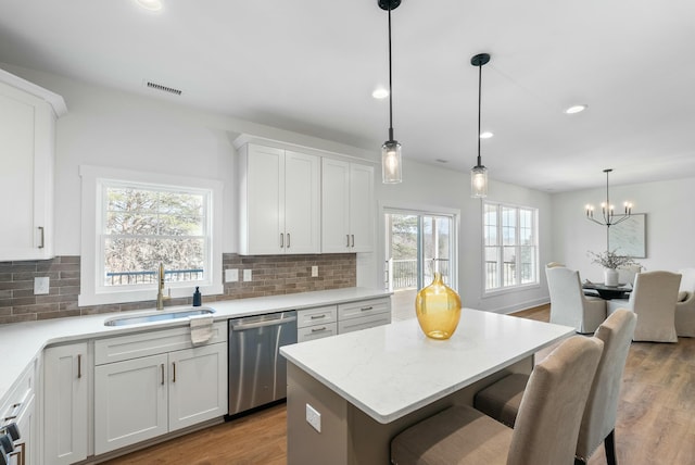 kitchen featuring stainless steel dishwasher, white cabinets, light wood-style floors, and a sink