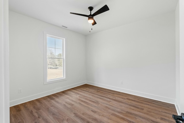 spare room with visible vents, baseboards, wood finished floors, and a ceiling fan