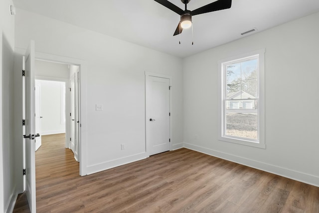 unfurnished bedroom featuring ceiling fan, baseboards, visible vents, and light wood-type flooring