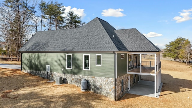 back of property with cooling unit and roof with shingles