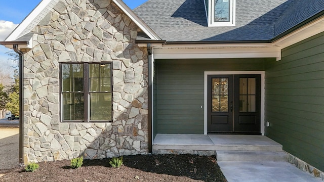 view of exterior entry with stone siding and a shingled roof