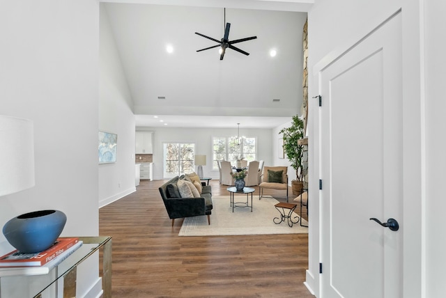 living room featuring ceiling fan with notable chandelier, wood finished floors, recessed lighting, a high ceiling, and baseboards