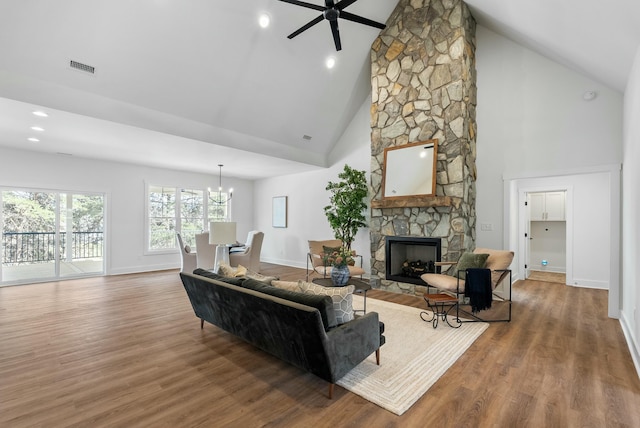 living area with visible vents, baseboards, a stone fireplace, and wood finished floors