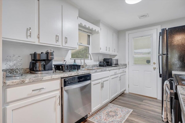 kitchen with a sink, visible vents, white cabinetry, and stainless steel appliances