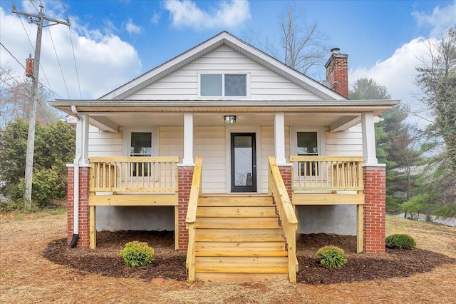 bungalow with stairs, a porch, and a chimney