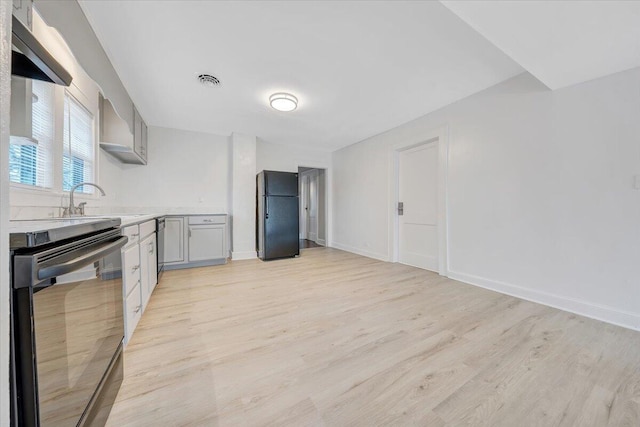 kitchen with dishwashing machine, light wood finished floors, light countertops, and freestanding refrigerator