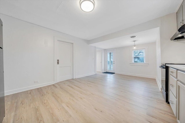 unfurnished living room featuring visible vents, light wood-type flooring, and baseboards