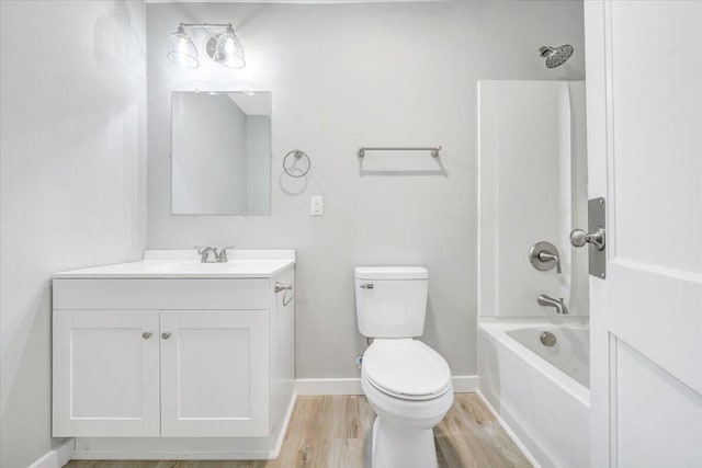 bathroom with vanity, wood finished floors, baseboards, shower / bath combination, and toilet