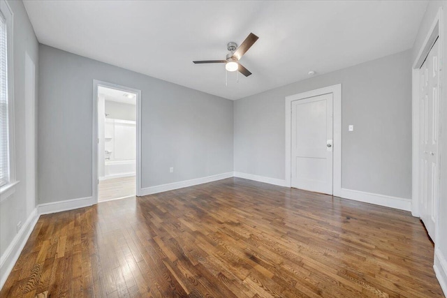 spare room with dark wood-style floors, baseboards, and ceiling fan