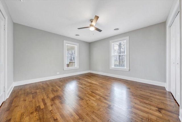 unfurnished bedroom with visible vents, multiple windows, wood finished floors, and a closet