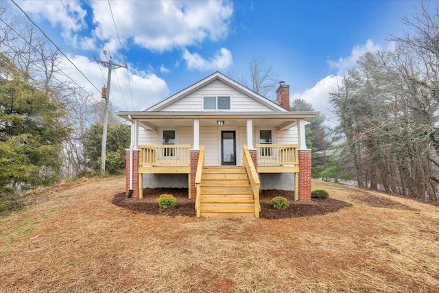 view of front facade with stairway, covered porch, and a chimney