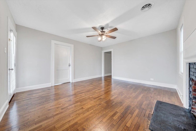 unfurnished living room featuring baseboards, visible vents, ceiling fan, hardwood / wood-style flooring, and a brick fireplace