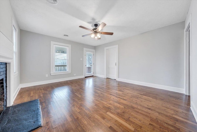 unfurnished living room with hardwood / wood-style floors, baseboards, a fireplace, ceiling fan, and a textured ceiling