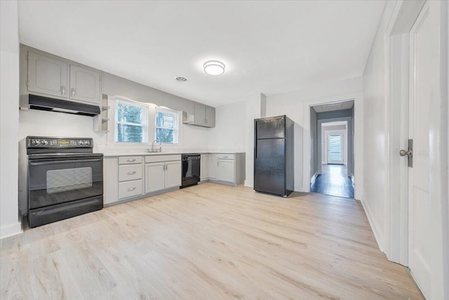 kitchen featuring black appliances, light wood-style floors, under cabinet range hood, and gray cabinetry