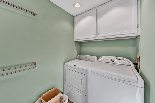 clothes washing area featuring cabinet space and washer and clothes dryer