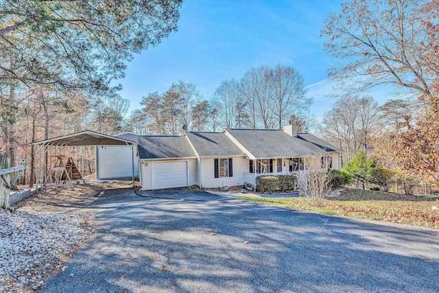 ranch-style home with a detached carport, a porch, a chimney, a garage, and driveway