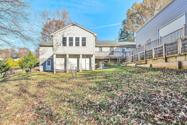 rear view of house with a wooden deck, a yard, and fence