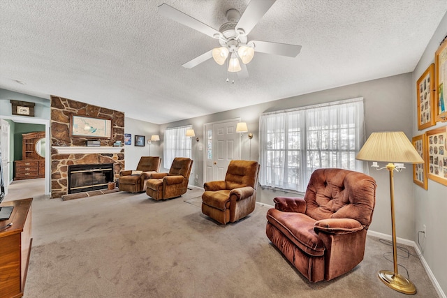 living room with lofted ceiling, a ceiling fan, carpet floors, a stone fireplace, and baseboards