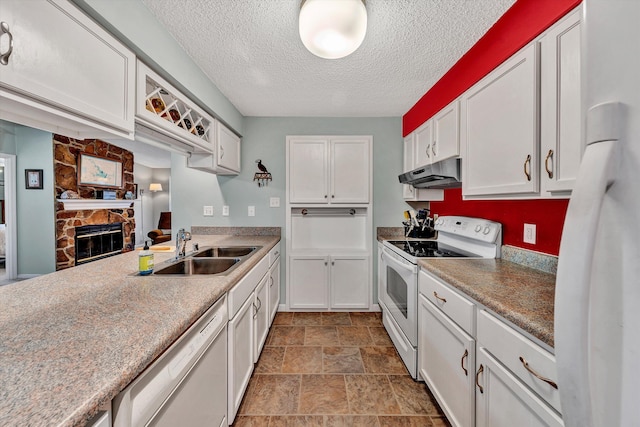 kitchen with under cabinet range hood, a sink, white cabinetry, white appliances, and a stone fireplace