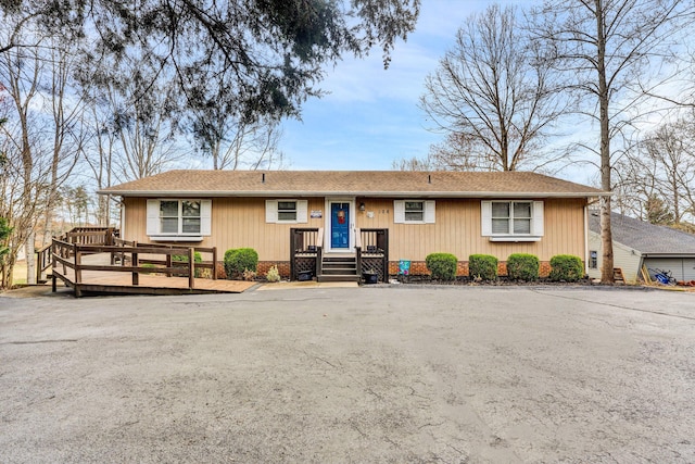 single story home with a wooden deck and a shingled roof