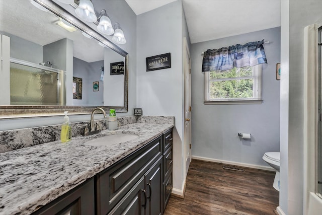 bathroom with vanity, wood finished floors, baseboards, a stall shower, and toilet