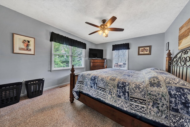 carpeted bedroom with ceiling fan, baseboards, and a textured ceiling