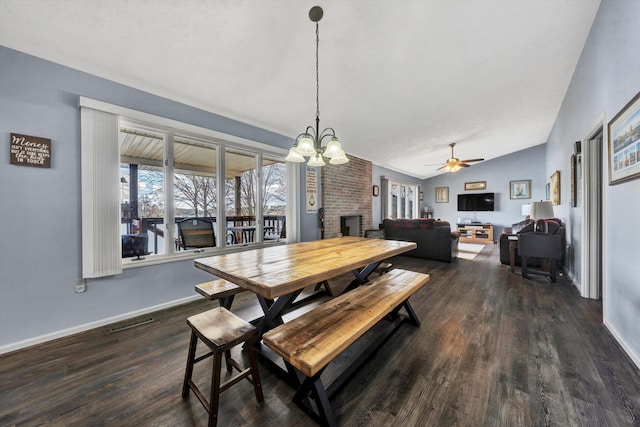 dining room with dark wood finished floors, lofted ceiling, a brick fireplace, and visible vents