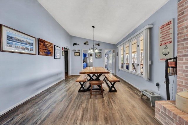 dining room with a chandelier, lofted ceiling, baseboards, and wood finished floors