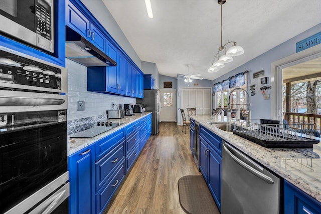 kitchen with backsplash, blue cabinetry, wood finished floors, stainless steel appliances, and a sink