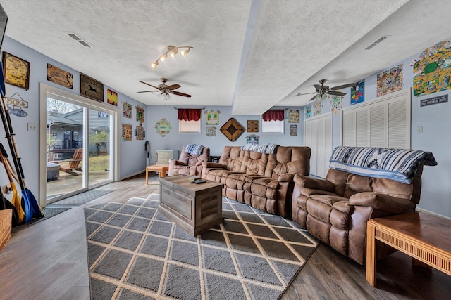 living area with visible vents, a textured ceiling, ceiling fan, and wood finished floors